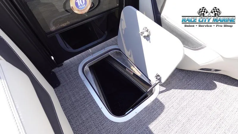 Slide: The Image of 2025 Barletta L25UCAT boat storage compartment with open hatch, gray carpet, Race City Marine logo. - 48