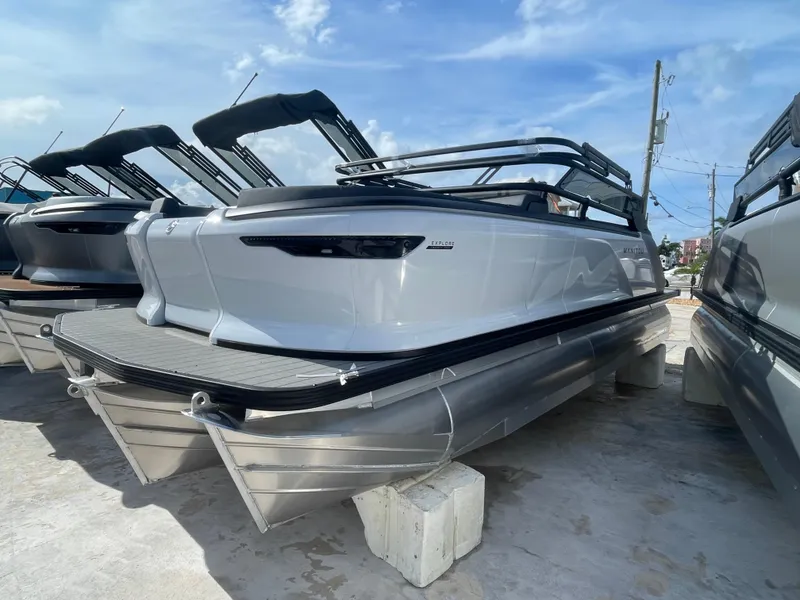 The Image of 2024 Manitou 22 Explore Switchback HSP575 pontoon boats on display under a clear sky. - 1