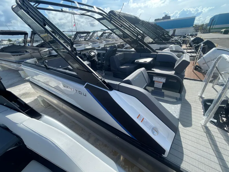 Slide: The Image of 2024 Manitou 22 Explore Switchback HSP575 boat, sleek design, docked under sunny skies. - 4