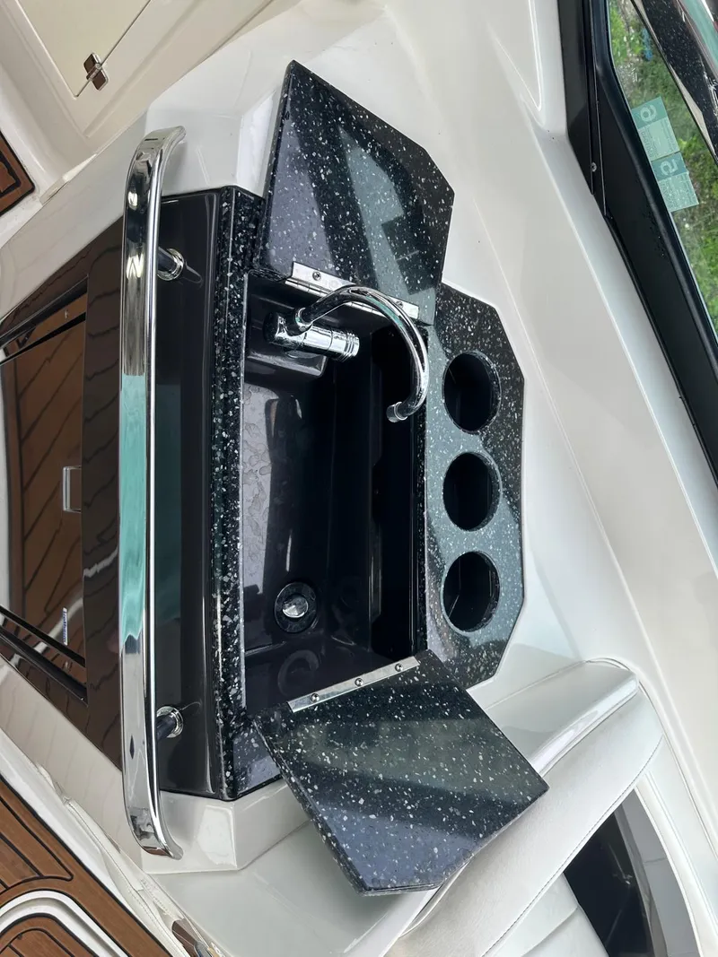 Slide: The Image of 2014 Monterey 328 Super Sport boat sink with black countertop and cup holders. - 23