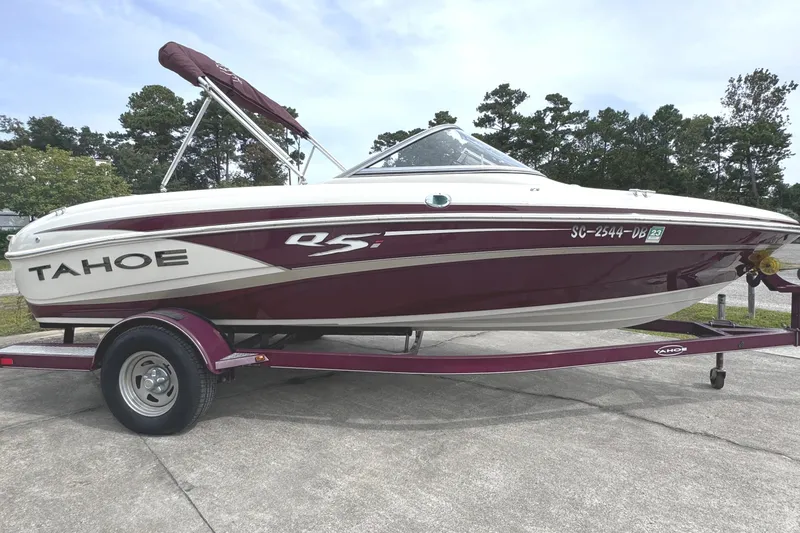 Slide: The Image of 2014 Tahoe Q5i boat on trailer, maroon and white, parked outdoors. - 13