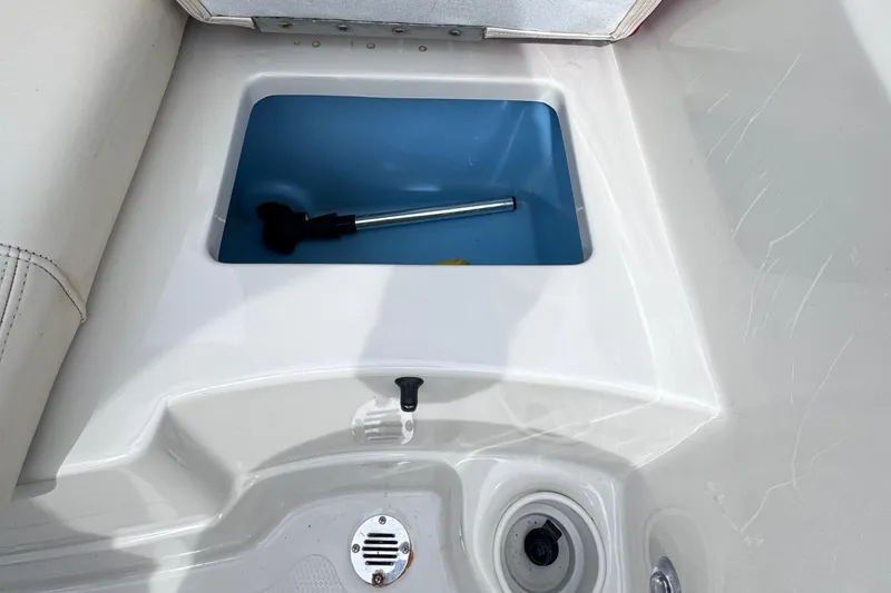 Slide: The Image of 2014 Tahoe Q5i boat storage compartment with blue interior and drain plug. - 8