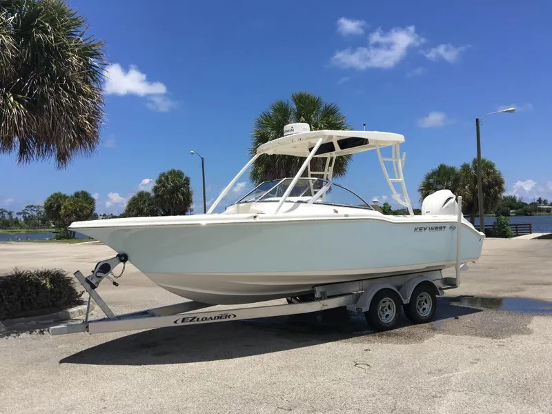 The Image of 2016 Key West 239 DFS boat on trailer, parked near palm trees under blue sky. - 1