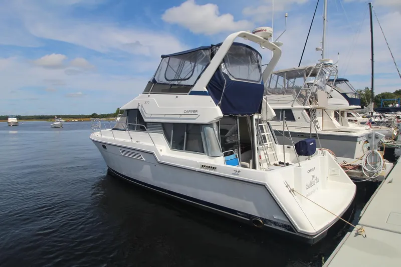 The Image of 1995 Carver 370 Voyager yacht docked at marina under blue sky. - 1