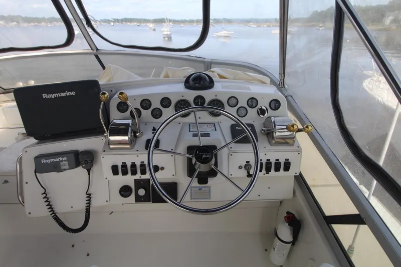 Slide: The Image of 1995 Carver 370 Voyager helm with Raymarine equipment, overlooking a serene waterway. - 3