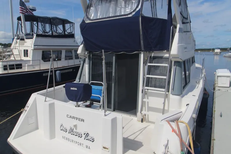 Slide: The Image of 1995 Carver 370 Voyager docked, featuring a spacious deck and blue canopy. - 41