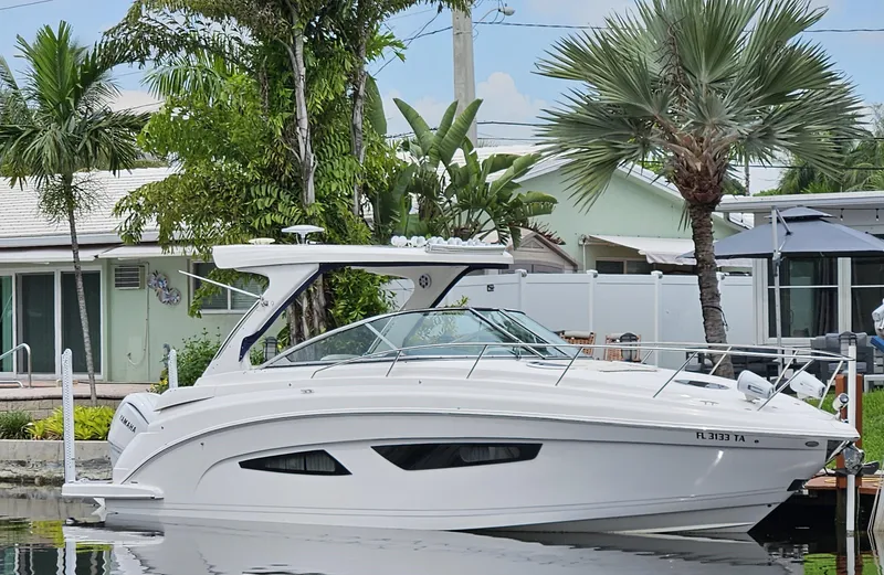 The Image of 2022 Regal 33 XO boat docked by tropical waterfront home. - 0