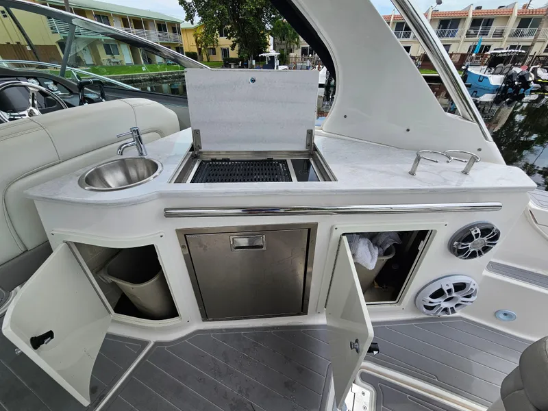 Slide: The Image of 2022 Regal 33 XO yacht kitchenette with sink, grill, and storage compartments. - 10