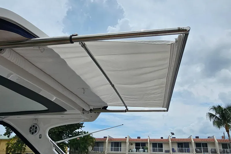 Slide: The Image of 2022 Regal 33 XO boat with extended sunshade against a cloudy sky. - 19