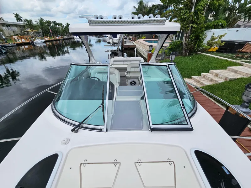 Slide: The Image of 2022 Regal 33 XO boat docked by a lush canal. - 2