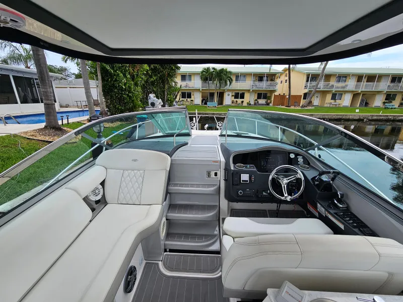 Slide: The Image of 2022 Regal 33 XO boat interior with modern helm and seating, docked near waterfront homes. - 8
