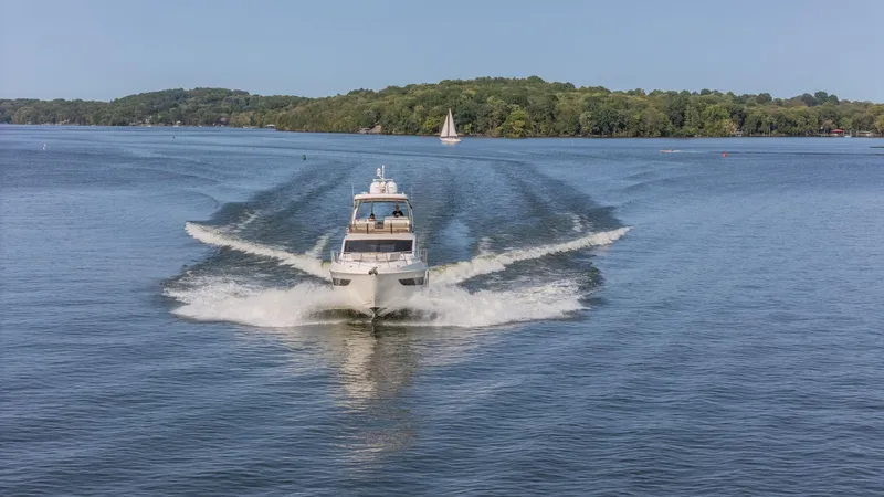 Slide: The Image of 2018 Sea Ray L550 Fly cruising on a serene lake with lush green shoreline. - 4