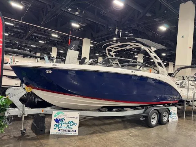 Slide: The Image of 2025 Yamaha Boats 252SE displayed indoors on a trailer at a boat show. - 0