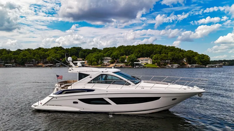 Slide: The Image of 2017 Regal 53 Sport Coupe yacht on a scenic lake with cloudy sky. - 2