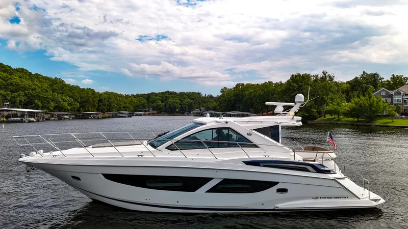 Slide: The Image of 2017 Regal 53 Sport Coupe yacht on a serene lake with lush green surroundings. - 5