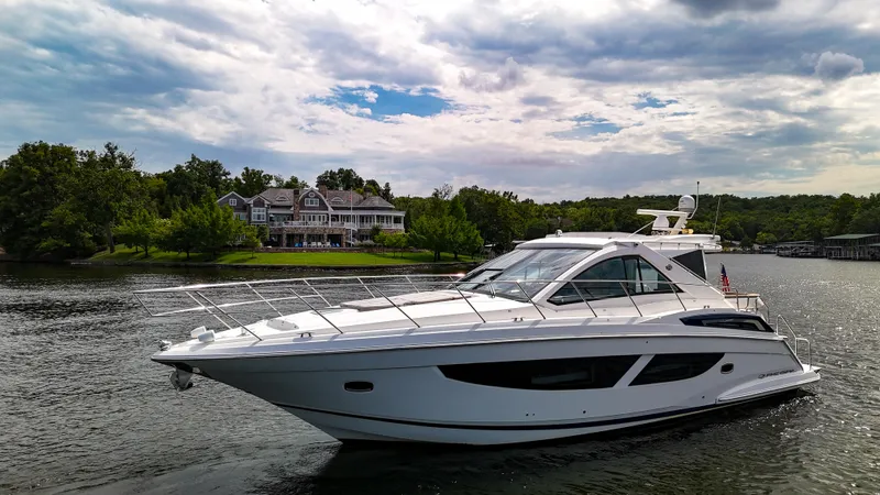 Slide: The Image of 2017 Regal 53 Sport Coupe yacht cruising on a scenic lake with lush greenery. - 8