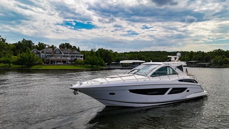 Slide: The Image of 2017 Regal 53 Sport Coupe yacht cruising on a scenic lake with houses in the background. - 9