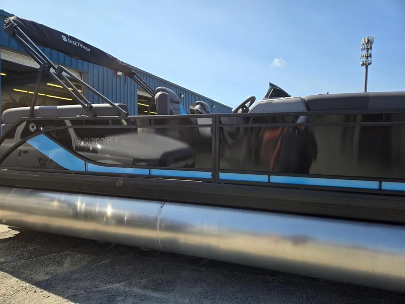 Slide: The Image of 2025 Godfrey Sweetwater 2486 SB pontoon boat, sleek design, parked outdoors. - 6
