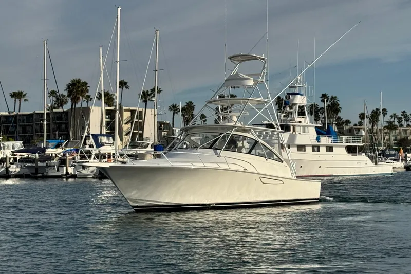 Slide: The Image of 2012 Viking 42 Open yacht cruising in a marina with sailboats and palm trees. - 10