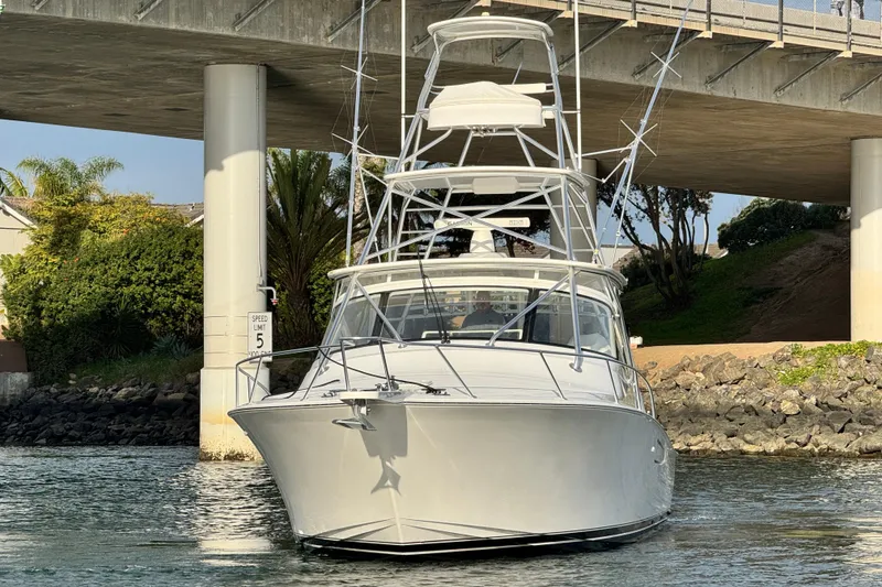 Slide: The Image of 2012 Viking 42 Open yacht under a bridge, surrounded by greenery and calm water. - 30