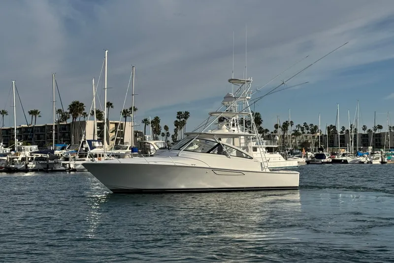 Slide: The Image of 2012 Viking 42 Open yacht docked in a marina with sailboats and palm trees. - 7