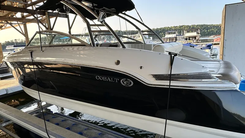 Slide: The Image of 2010 Cobalt 276 boat docked at marina, sleek black and white design. - 2