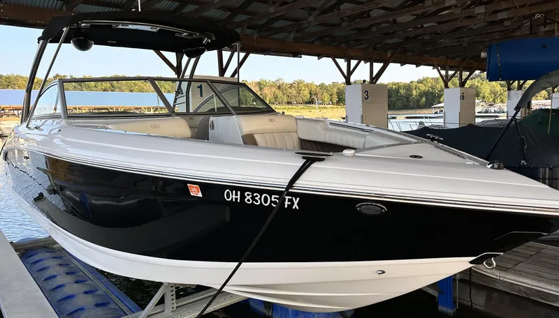 Slide: The Image of 2010 Cobalt 276 boat docked under a covered marina, black and white exterior. - 3