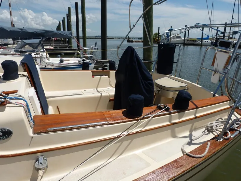 Slide: The Image of 1991 Island Packet 29 sailboat docked at marina, featuring wooden trim and covered equipment. - 11