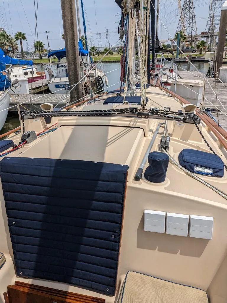 Slide: The Image of 1991 Island Packet 29 sailboat deck with blue cushions, docked in a marina. - 13