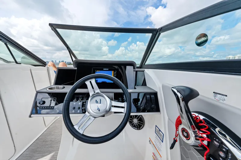 Slide: The Image of 2023 Sea Ray SDX 270 Outboard dashboard with steering wheel and controls, under a blue sky. - 25