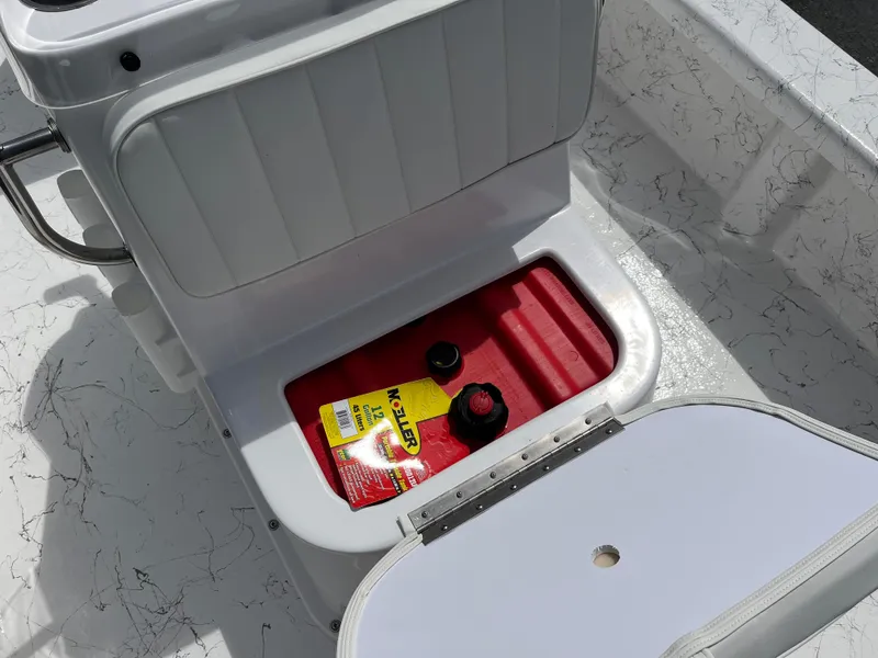 Slide: The Image of Open storage compartment in 2025 Coastal Skiff 171 boat, showing red container and items. - 9