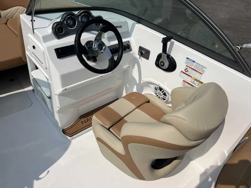 Slide: The Image of 2025 NauticStar 223 DC boat cockpit with steering wheel and beige seating. - 3