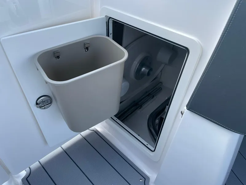 Slide: The Image of 2025 Chaparral 270 OSX boat storage compartment with integrated trash bin. - 31