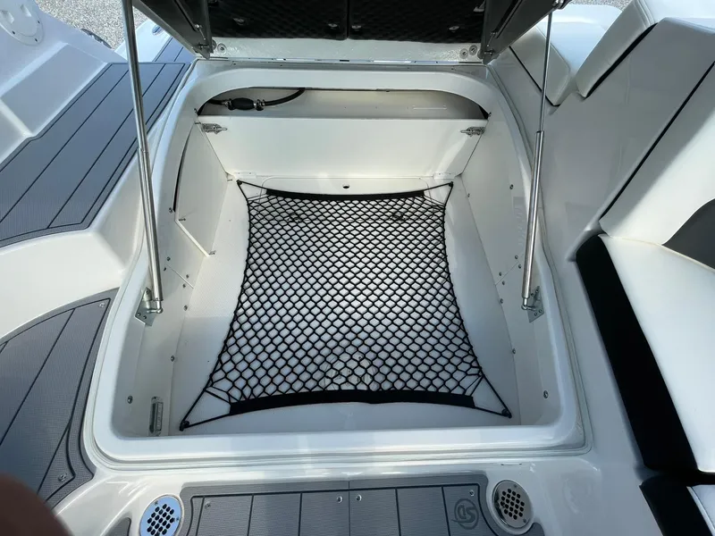 Slide: The Image of 2025 Chaparral 270 OSX boat storage compartment with netting and open hatch. - 41