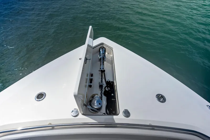 Slide: The Image of 2022 Scout LXF boat bow with anchor compartment, floating on clear water. - 26