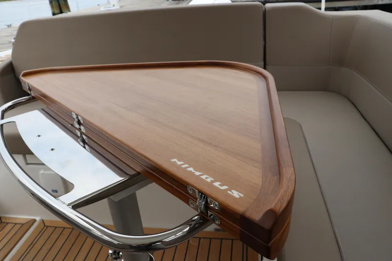 Slide: The Image of 2024 Nimbus Weekender 9 boat interior with wooden table and cushioned seating. - 22
