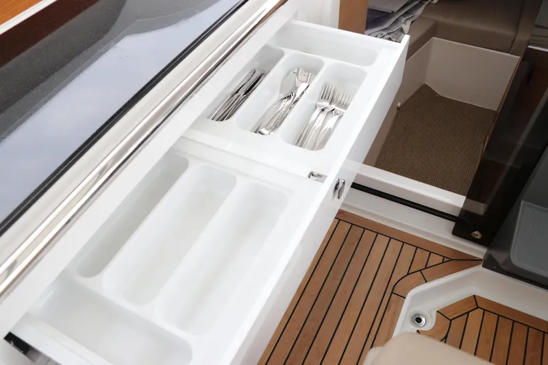 Slide: The Image of 2024 Nimbus Weekender 9 boat interior with open cutlery drawer on wooden deck. - 37