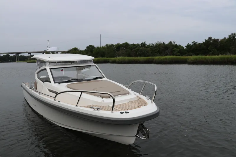 Slide: The Image of 2024 Nimbus Weekender 9 boat on calm water, surrounded by lush greenery. - 6