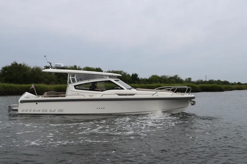 Slide: The Image of 2024 Nimbus Weekender 9 boat cruising on a calm river. - 8