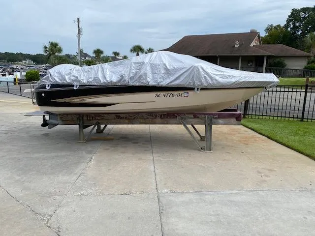 Slide: The Image of 2004 Glastron 185 GX boat covered on a lift, parked near a house. - 11