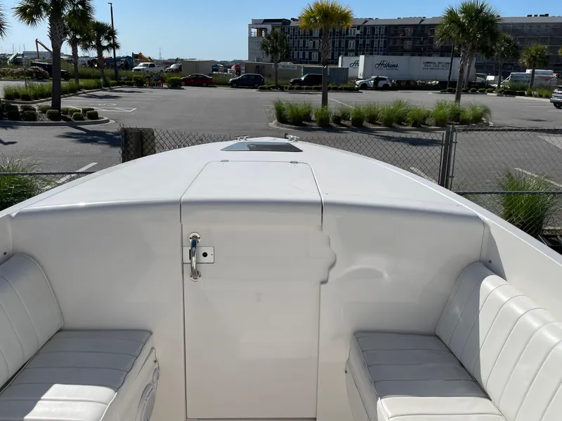 Slide: The Image of 2008 Intrepid 323 Cuddy boat with white seating, parked near palm trees. - 17