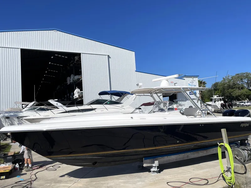 Slide: The Image of 2008 Intrepid 323 Cuddy boat docked near a large warehouse. - 2