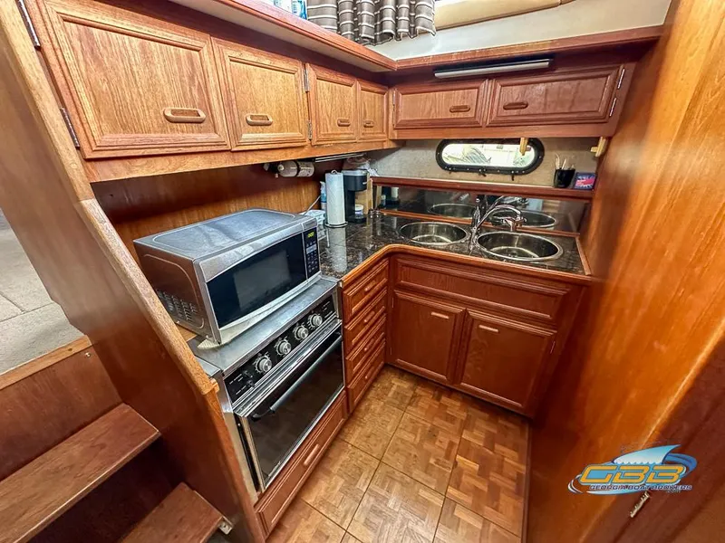 Slide: The Image of 1989 Carver 3807 Aft Cabin kitchen with wood cabinets, microwave, and dual sinks. - 23