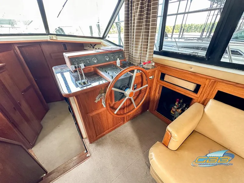 Slide: The Image of 1989 Carver 3807 Aft Cabin interior helm with wooden steering wheel and beige seating. - 35