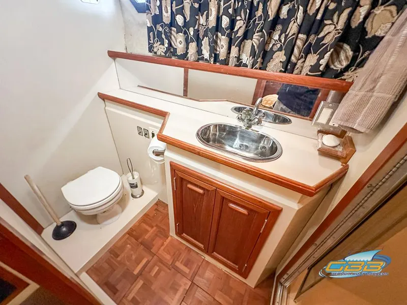 Slide: The Image of 1989 Carver 3807 Aft Cabin bathroom with sink, toilet, and wood accents. - 44