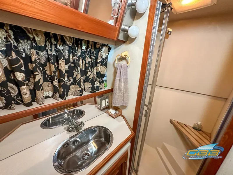 Slide: The Image of 1989 Carver 3807 Aft Cabin bathroom with sink, floral curtains, and shower. - 45
