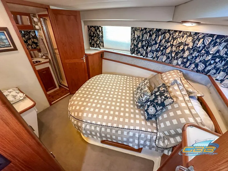 Slide: The Image of 1989 Carver 3807 Aft Cabin bedroom with patterned bedding and floral curtains. - 47