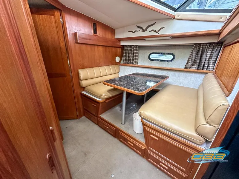 Slide: The Image of 1989 Carver 3807 Aft Cabin interior with dining area, wood finish, and cushioned seating. - 27