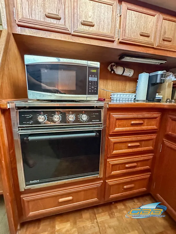Slide: The Image of 1989 Carver 3807 Aft Cabin kitchen with microwave and oven, wooden cabinetry. - 30