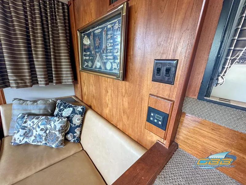Slide: The Image of 1989 Carver 3807 Aft Cabin interior with wood paneling, artwork, and cushioned seating. - 40